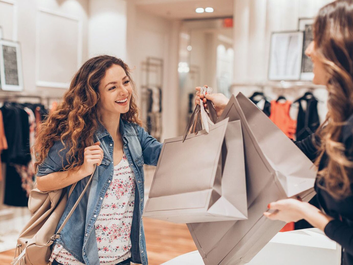 A saleswoman giving shopping bags to a woman in a fashion store