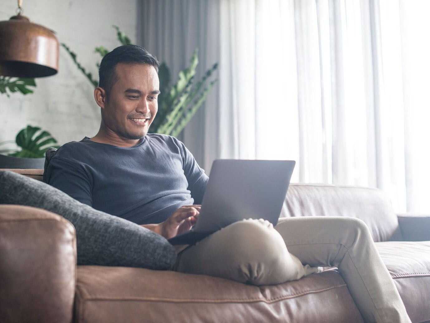 A young man using the laptop in the living room