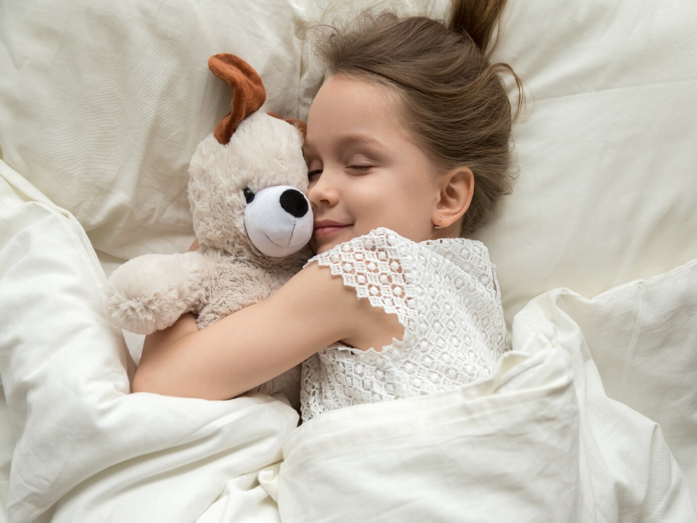 YORK Indoor Air Quality system used for a healthy indoor environment in home of a young girl laying in bed hugging her bear.