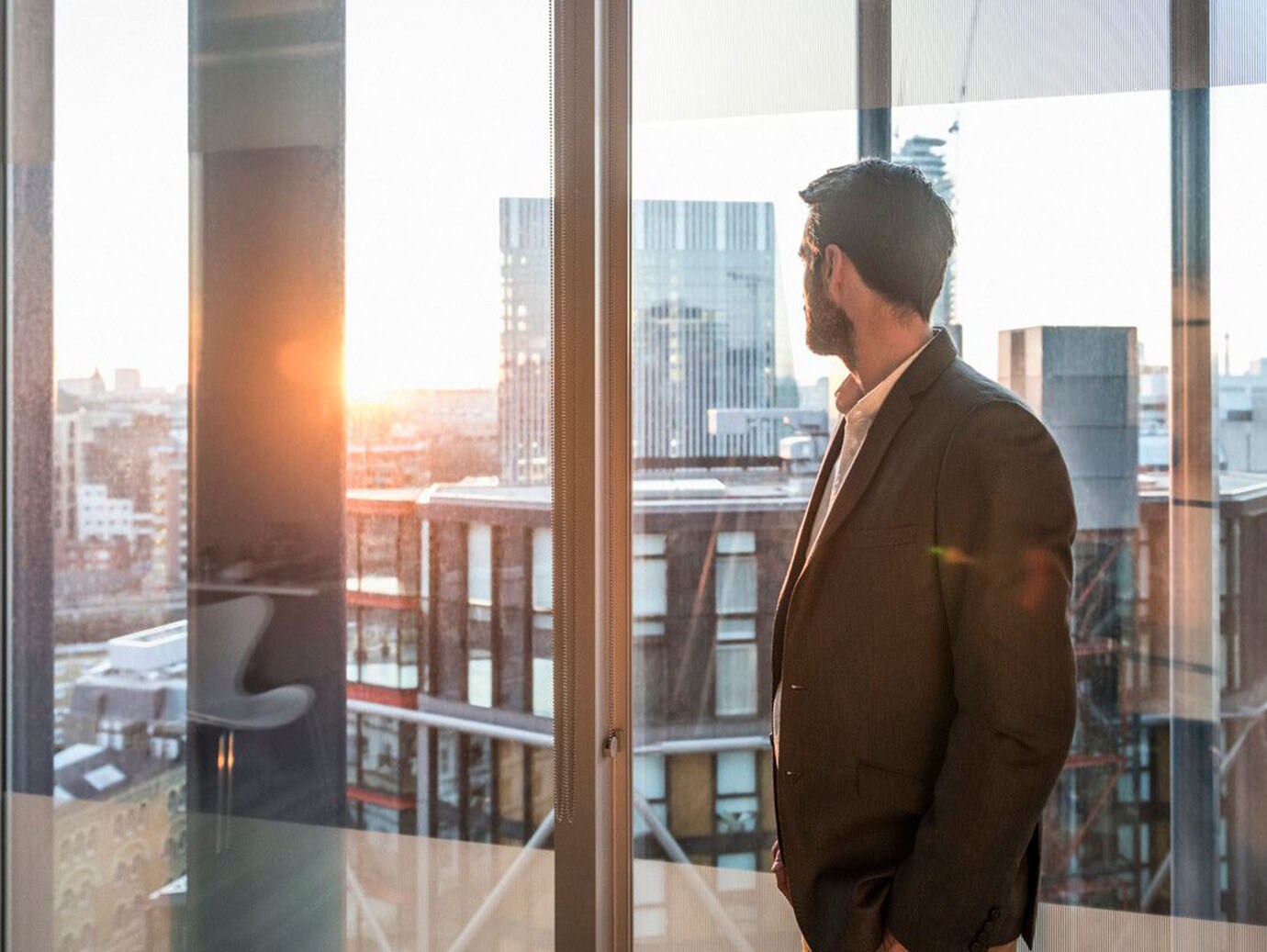 Office worker looking at view through window of modern office over city