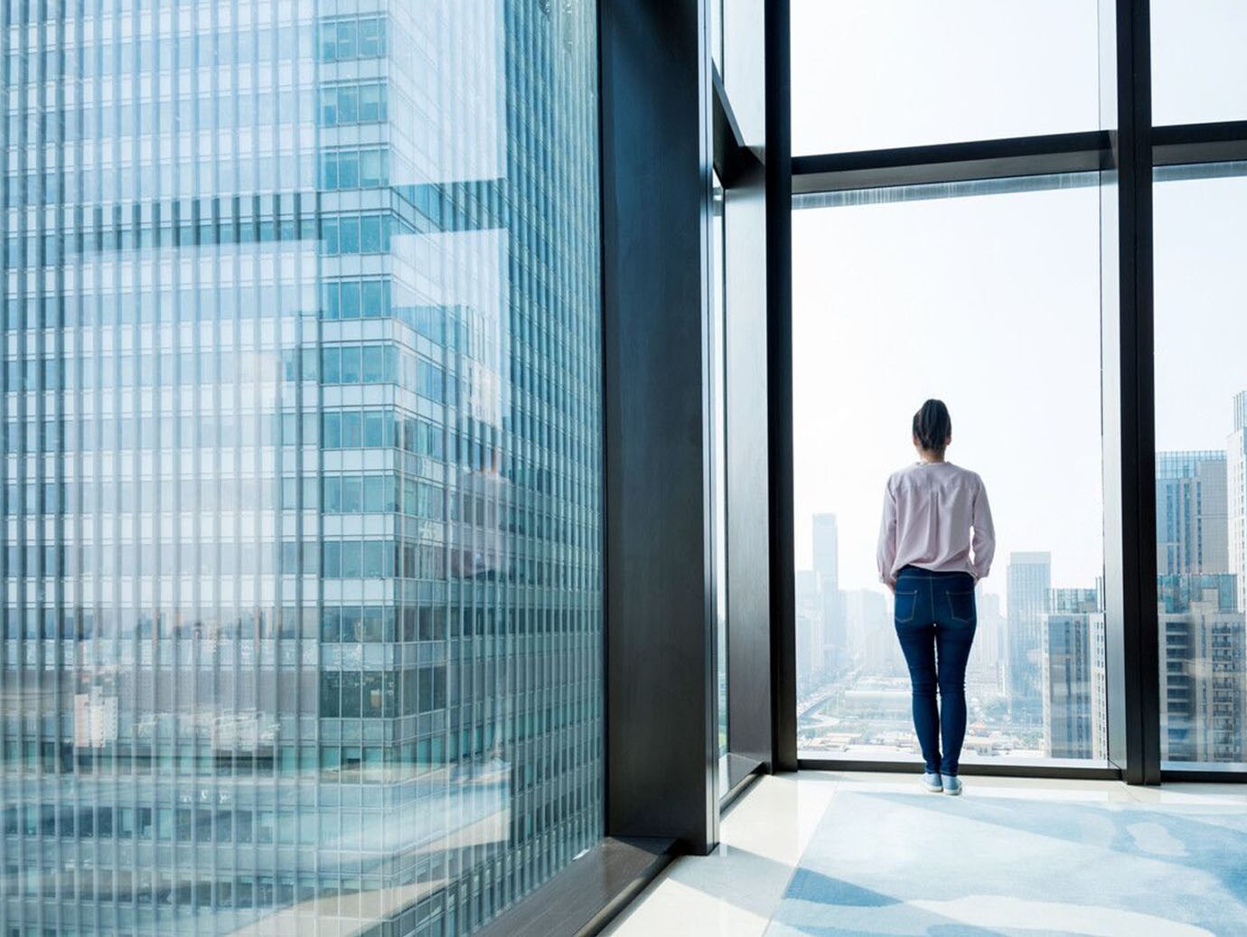 Woman standing and looking at cityscape from office