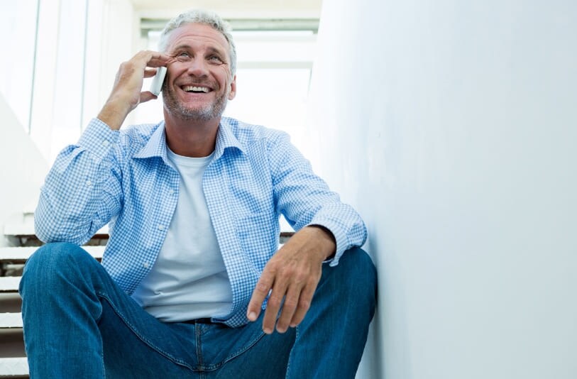 A man sitting on stairs and talking on a cell phone.
