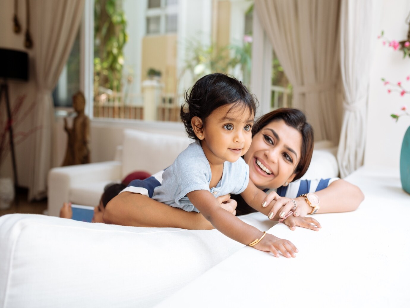 Happy child and mother play on the couch in home that uses a YORK Air Conditioner for reliable operation and comfort.