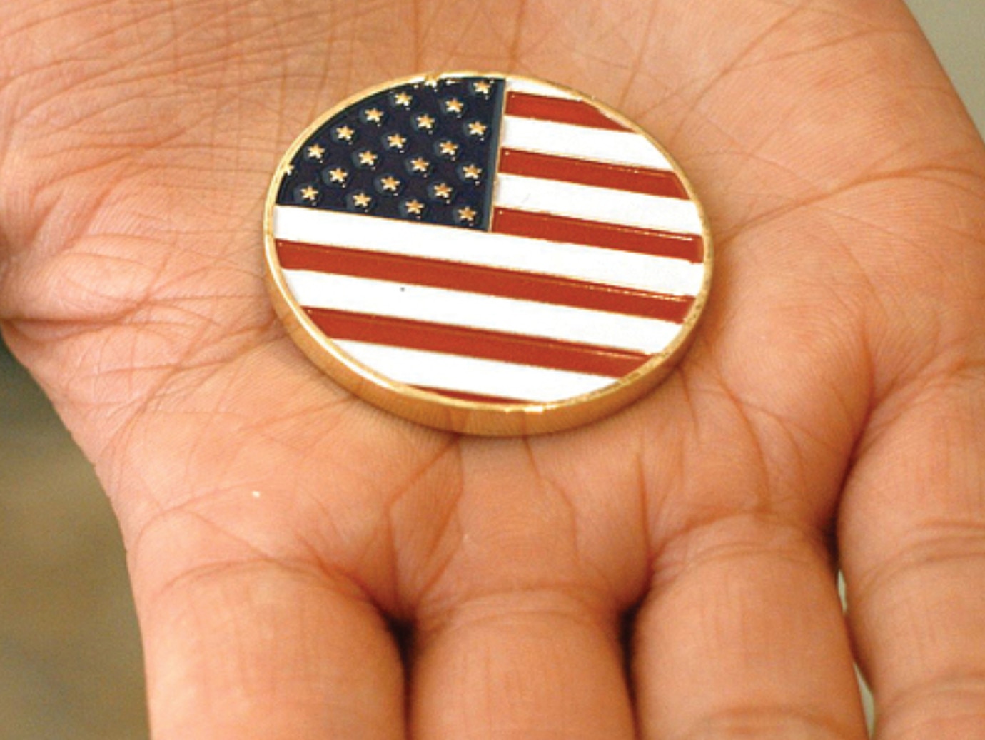 A hand holding United States flag badge